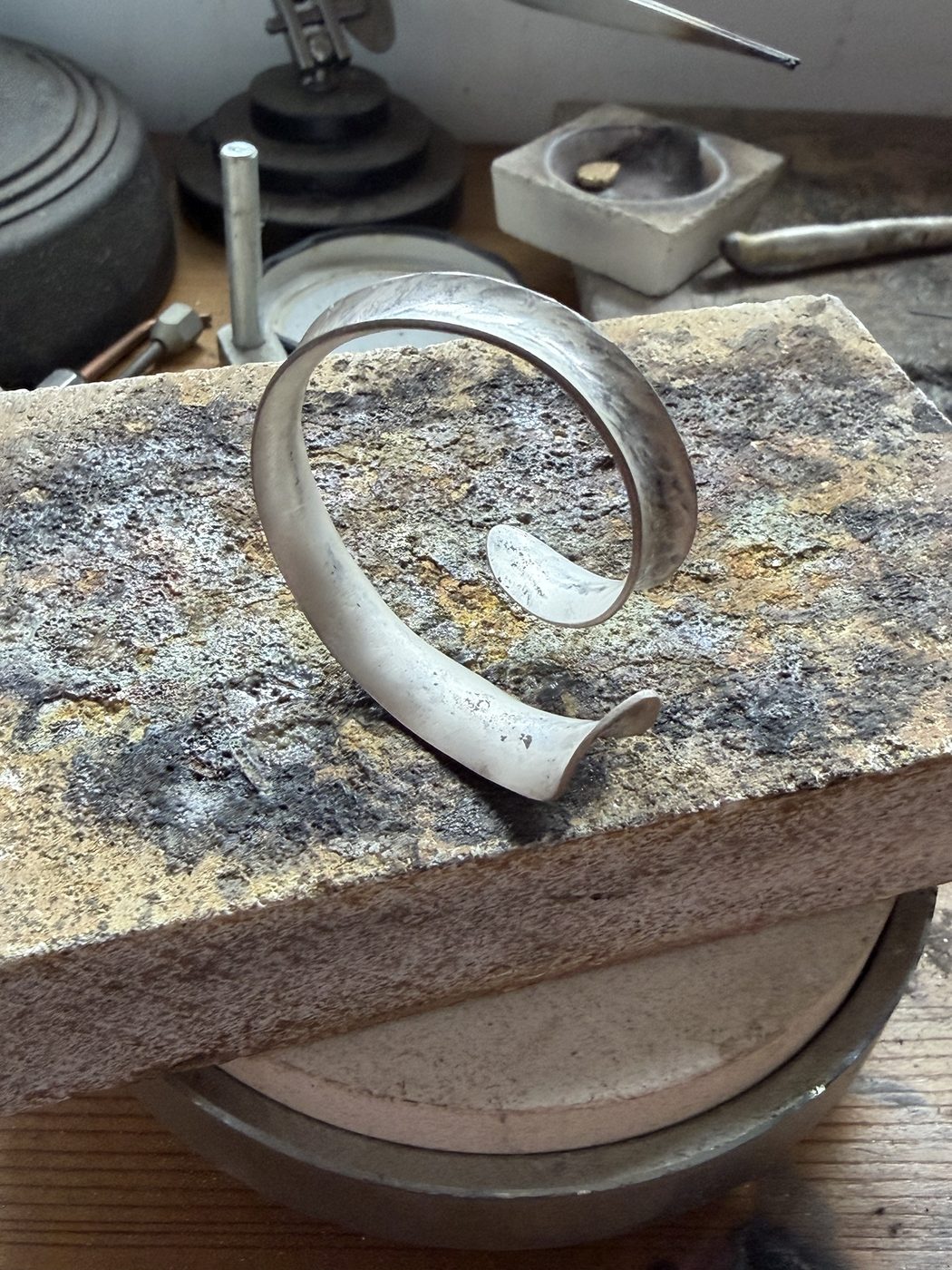 Open spiral cuff resting on a firebrick at the bench