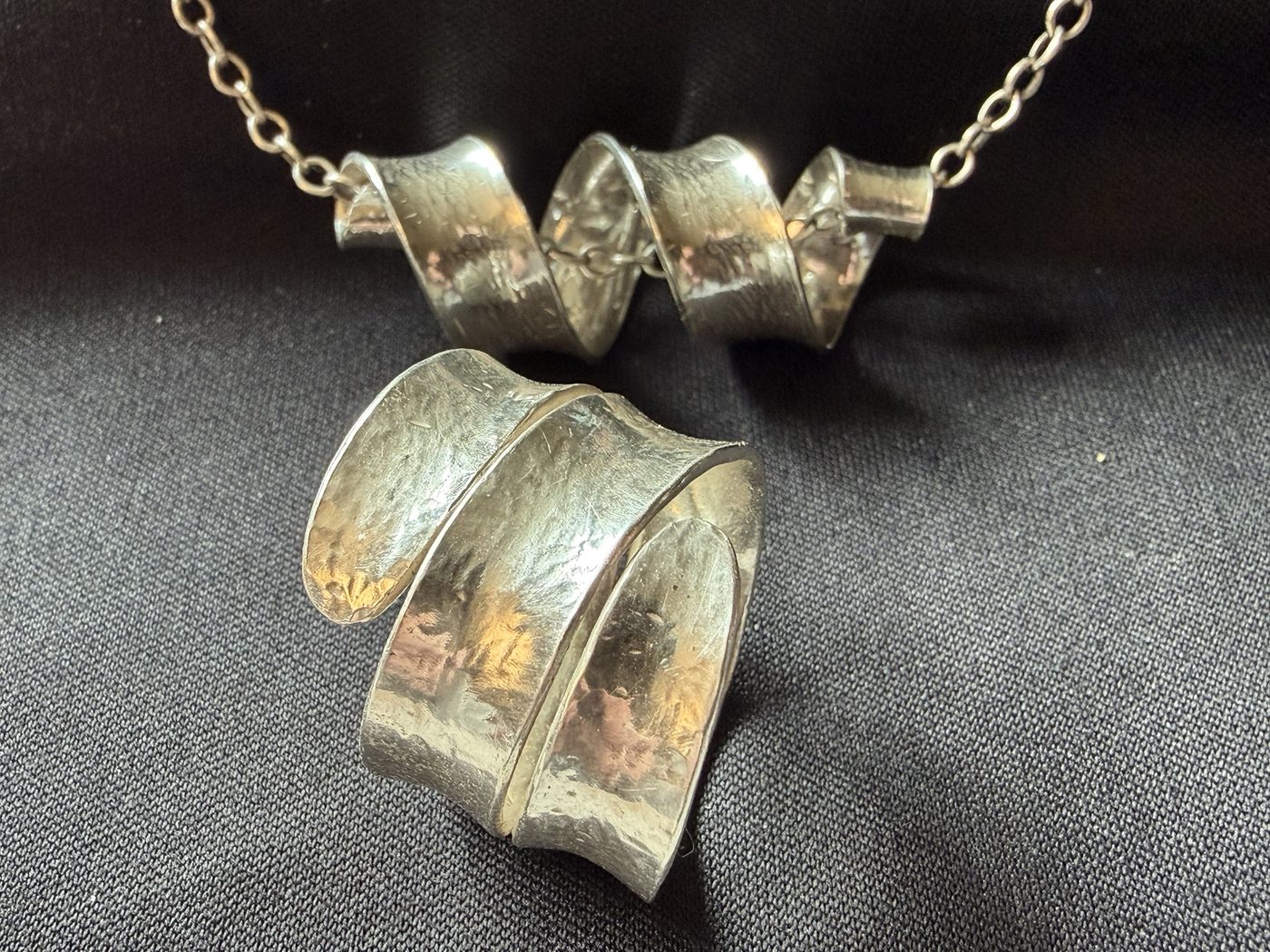 Spiral pendant above a wrap ring on black cloth
